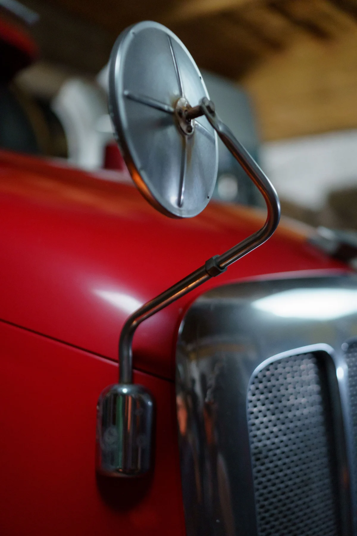 Close-up of a red classic car and its chrome mirror